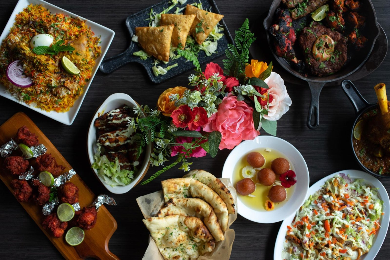 An overhead spread of Naan Curry Grill dishes — biryani, samosas, tandoori, naan and gulab jamun